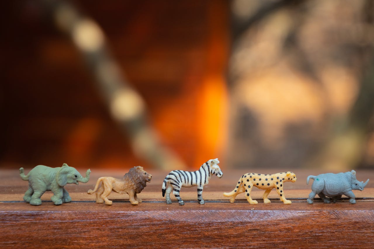 services-01 Miniature toy animals in a row on wood, displaying various wild species.