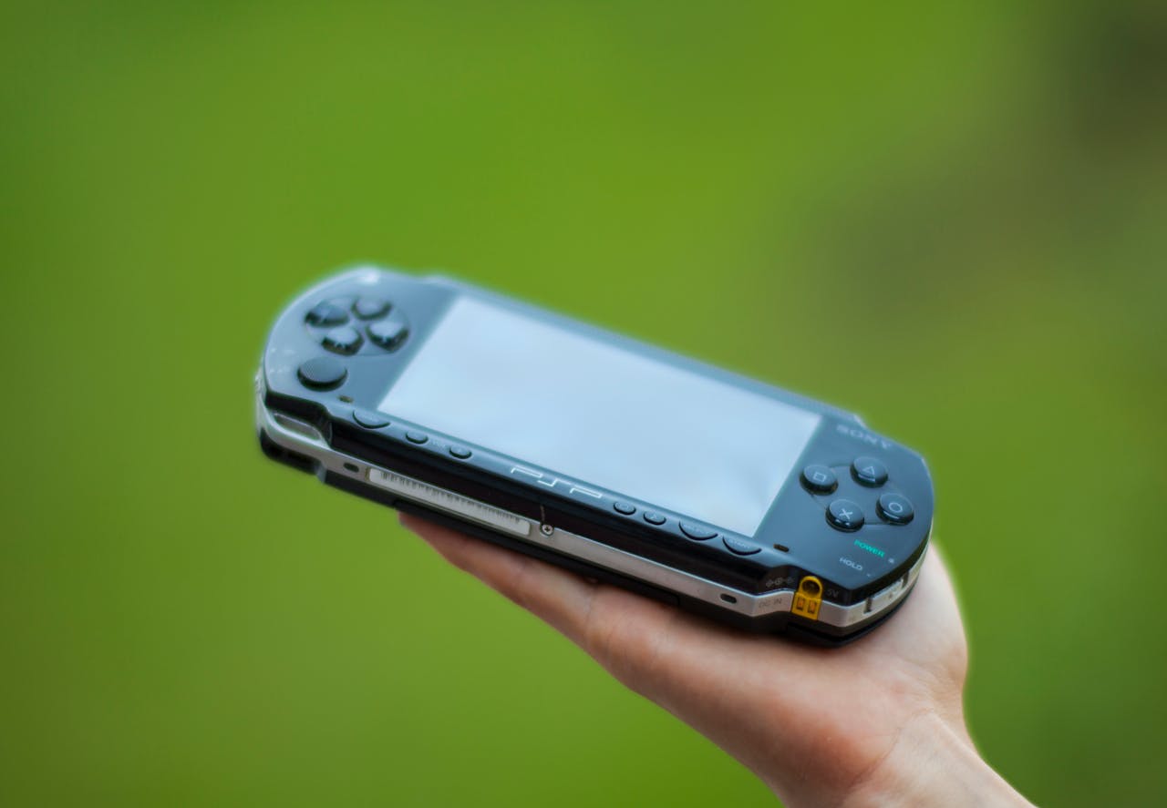 about-01 A hand holding a portable gaming console against a vibrant green background, showcasing modern technology.