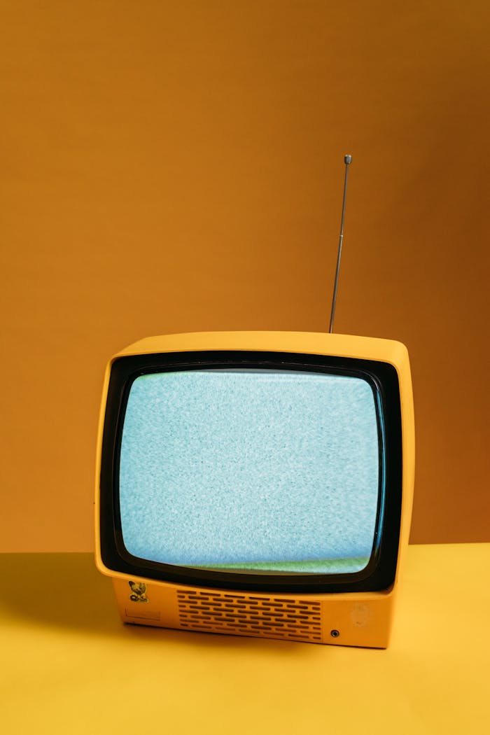 services-03 Retro yellow television on orange backdrop with static screen, perfect for vintage themes.